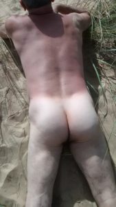 Tanned semi naked male escort in sand dunes